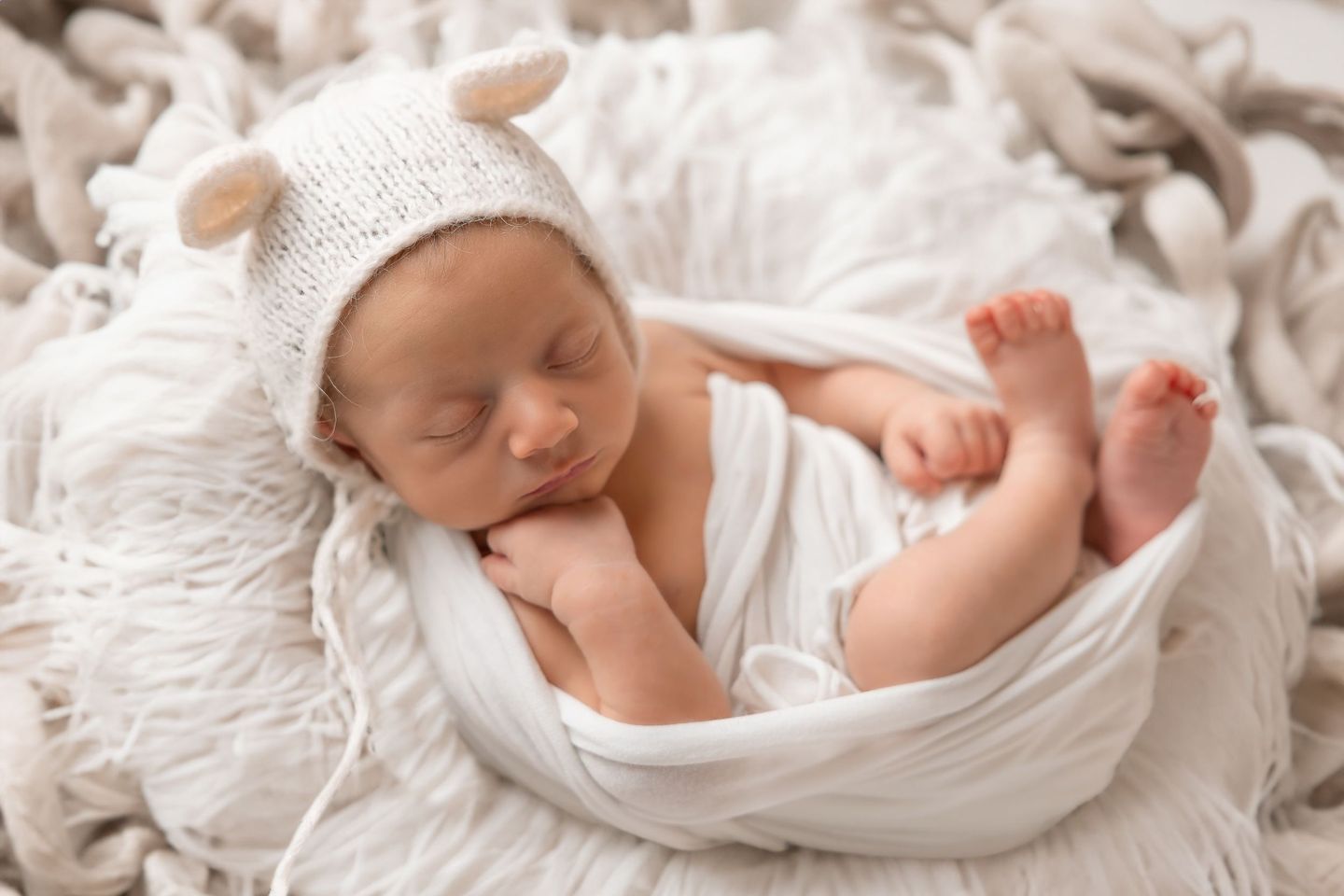 Neonato addormentato con il cappellino bianco, avvolto nel telo
