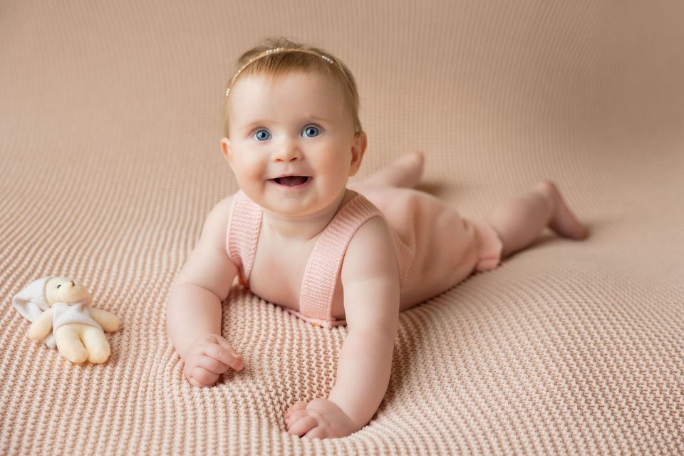 Bambina che sorride appoggiata sui gomiti