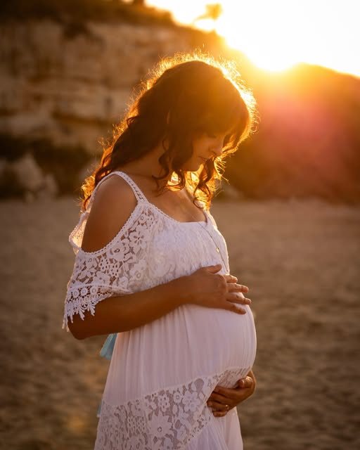 Ritratto in gravidanza controluce al tramonto sulla spiaggia