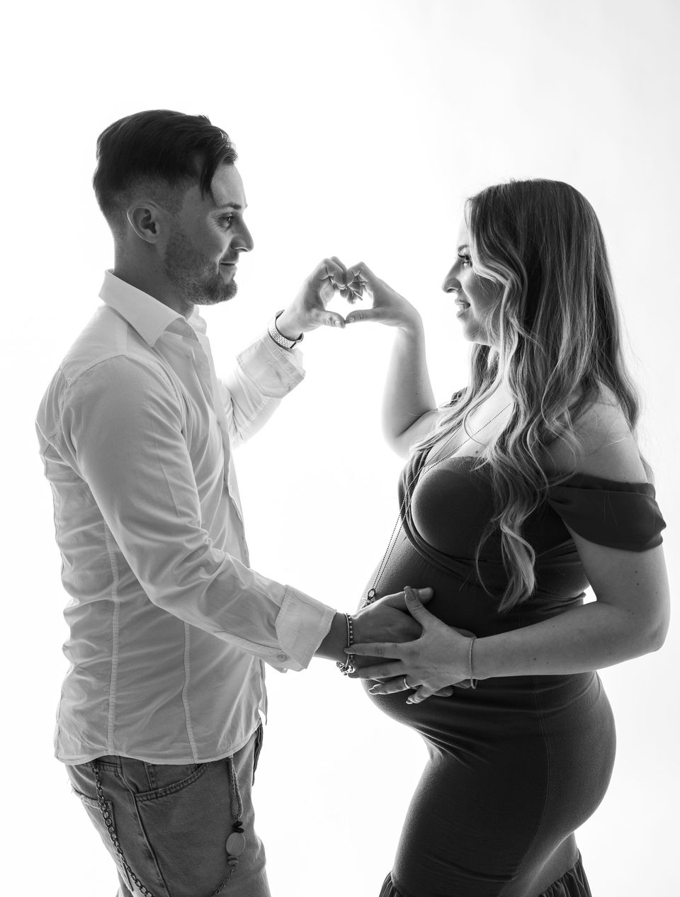 La coppia forma un cuore con le mani sul pancione