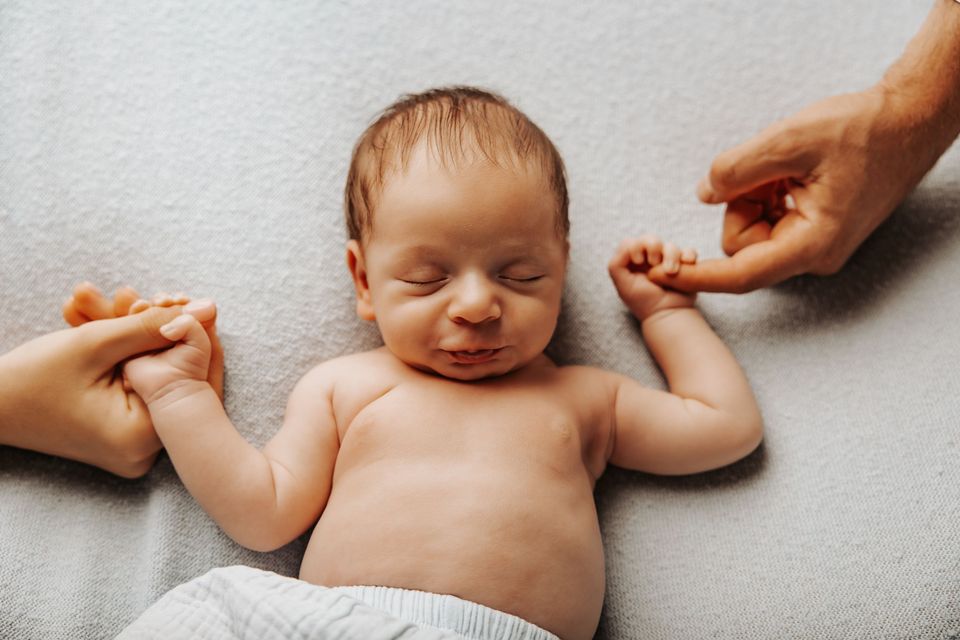 La mano di un adulto sfiora il neonato addormentato