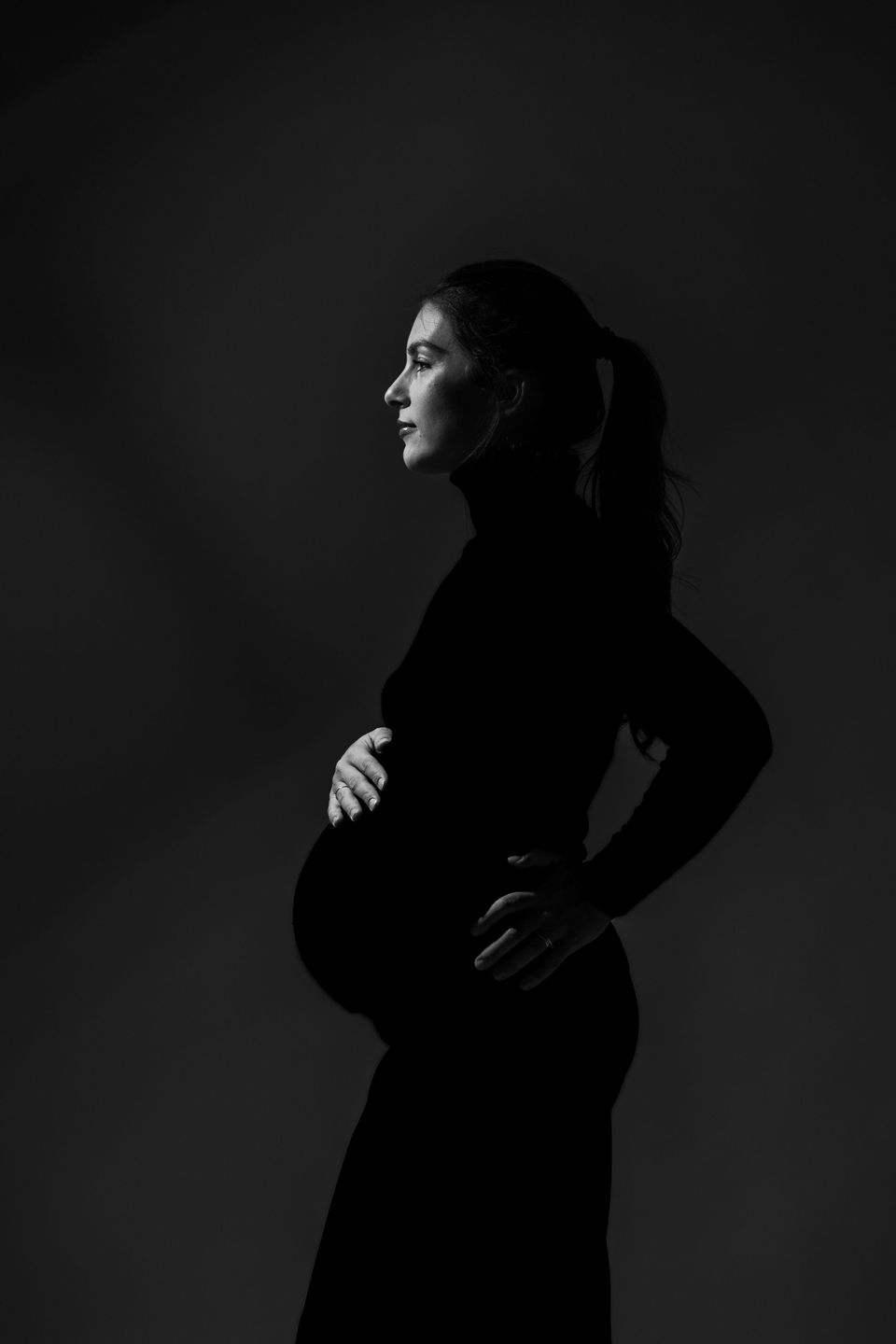Silhouette di una donna incinta su fondo scuro